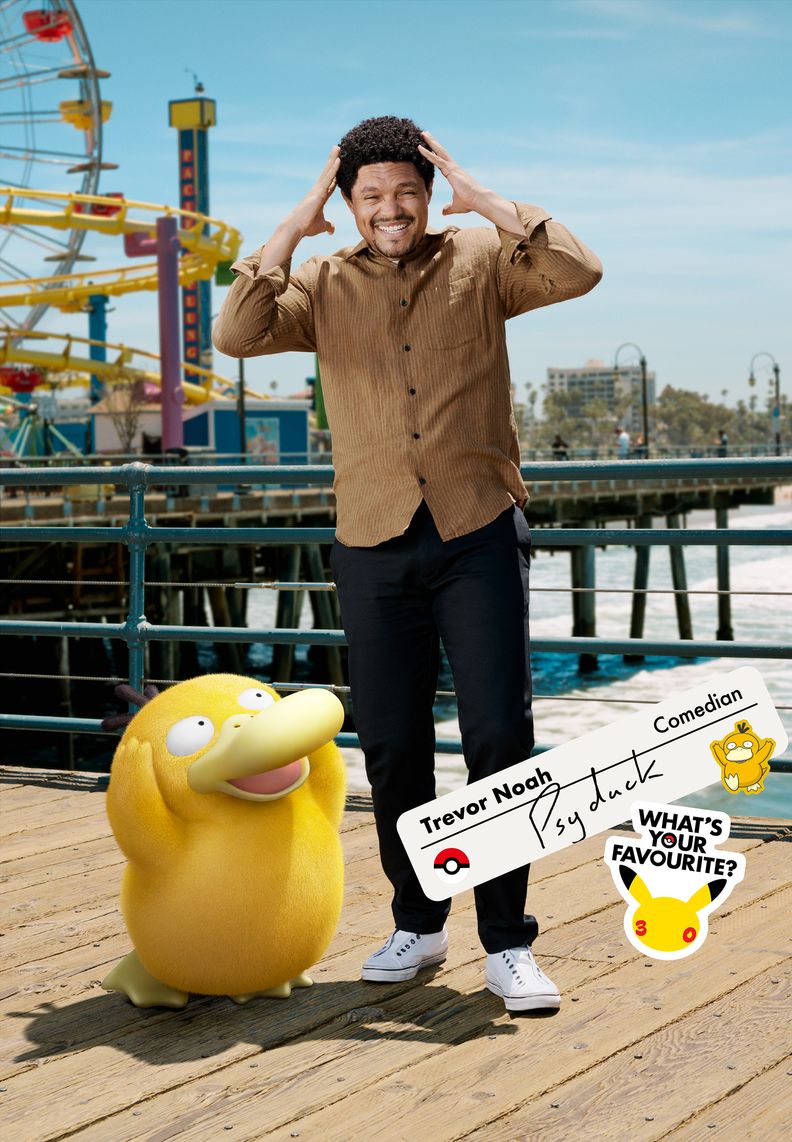 Comedian Trevor Noah stands on a pier next to Psyduck. Trevor’s hands are held near his temples as he recreates his Pokémon’s iconic pose.